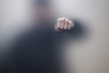 Male fist behind matte glass, abstract photo