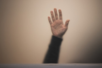 Blurred male hand behind matte glass wall, abstract