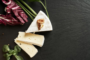 Delicious brie cheese on black background. Brie type of cheese. Camembert. Fresh Brie cheese and a...