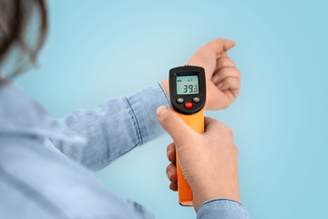 Young adult asian girl checking temperature with infrared thermometer