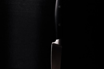 Black kitchen knife stands blade down