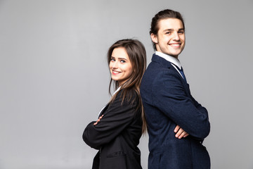 Two young business people standing back to back with hands crossed isolated on grey background