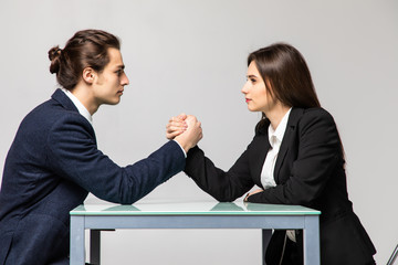 Business man and woman are fighting in their arms, arm wrestling between male and female. Family quarrel, showdown, division of property, divorce.