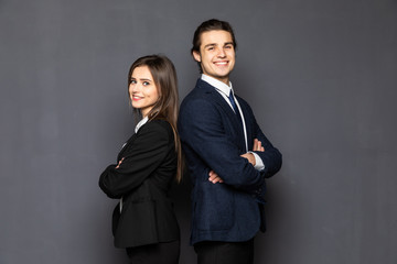 Business man and woman standing back to back isolated on gray background. Teamwork concept