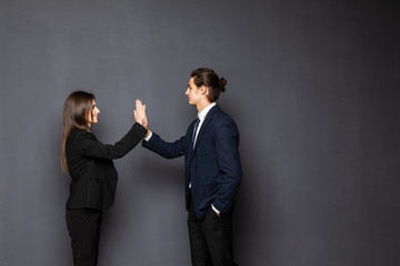 Executive business man and woman give high five and looks satisfied isolated on gray background