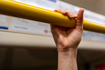 closeup woman hand holding handrail (grip) inside a train in London. Virus hygiene and safety.