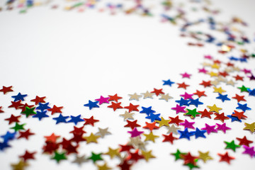 Confetti stars on white background, festive colorful and shiny stars on white background with copy space.