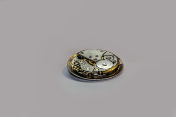 Vintage watch mechanism from and old mechanical clock with steel gears on a grey background