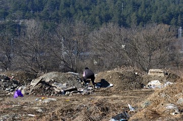 the woman is looking for something by the trash