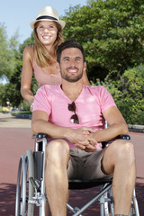 happy couple in wheelchair strolling in the park