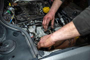 The mechanic bleeds the fuel system with a pump that is on the fuel line, after installing a new fuel filter, the man's hands are visible.