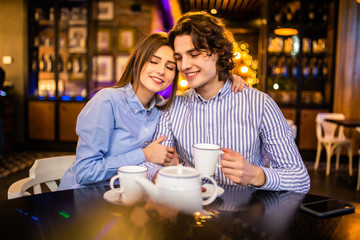 Happy young man and woman drinking tea in cafe