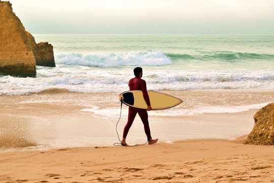 surfista sulla spiaggia dos Três Irmãos  situata ad Alvor nell'Oceano Atlantico nella regione dell'Algarve in Portogallo