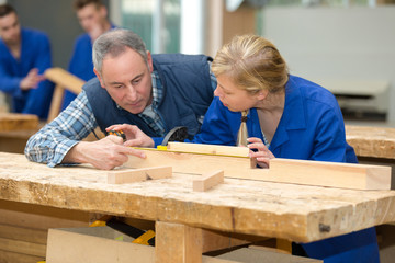 carpenter teaching apprentice how to cut wood