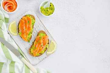 Avocado toasts. Toasts from rye bread, avocado, smoked salmon, green onions and sesame seeds. Healthy breakfast or lunch. Horizontal orientation. Top view. Copy space.