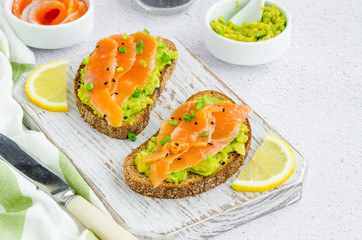 Avocado toasts. Toasts from rye bread, avocado, smoked salmon, green onions and sesame seeds....