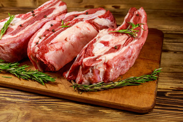 Raw pork ribs with spices and rosemary on wooden table