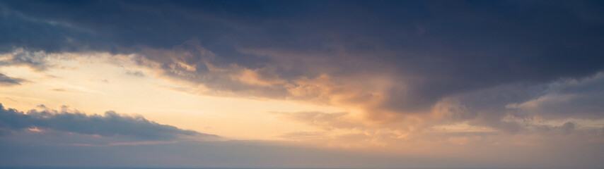 Fototapeta na wymiar Large panorama of evening sunset sky with dark blue clouds.