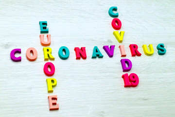 Coronavirus COVID-19 in EUROPE - Rainbow colored wood letters on grey wooden background