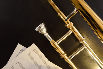 Mouthpiece and trombone braces detail on black table and scores