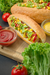 Hot dog with sausage, corn and lettuce on a wooden board. Fast food. Calorie content of food. Close-up. Side view.