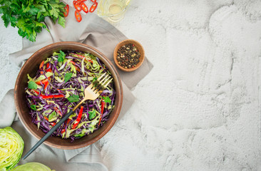 Bright salad of purple cabbage, white cabbage, bell pepper in a plate on a light table. Bright salad of fresh vegetables. Food background. Vegetarian dish. View from above. Copy space