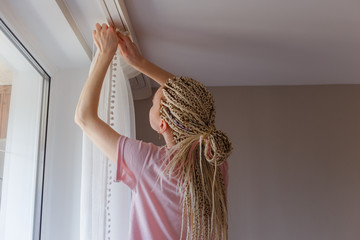 Woman hanging up curtains at the window