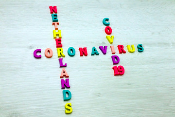 Coronavirus COVID-19 in NETHERLANDS - Rainbow colored wood letters on grey wooden background