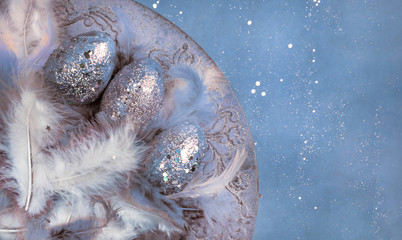 easter eggs, feathers with festive glitter confetti on creative toned background