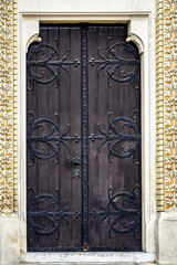 Antique wooden door decorated with wrought iron decorative elements.