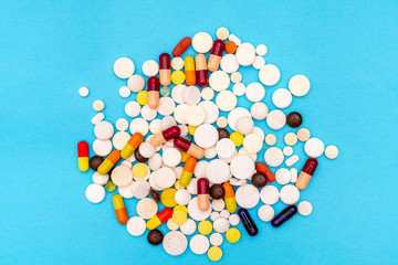 Various pills on a blue background, top view close up