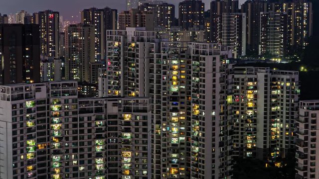 Day to night time lapse of apartments buildings in China. Timelapse of residential flats windows lighting up and turning off overnight in Shenzhen. Modern life in crowded massive apartment buildings.