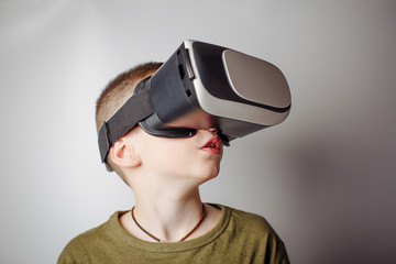 Boy playing mobile game app on device virtual reality glasses on white background. Boy action and using in virtual headset, VR box for use with smart phone. Contemporary technology concept