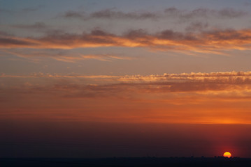 Sunset in the city. Beautiful sunset sky and sun and a contrasting panorama of the city at the bottom of the photo.