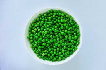 Peeled green peas in a white bowl on a white background. The concept of proper nutrition.