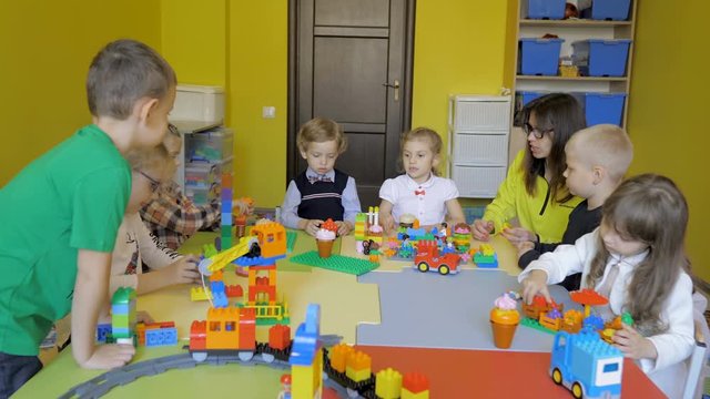 Children in the classroom make figures with teacher. Modern technology concept