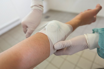 A doctor puts on a pressure bandage in a hospital