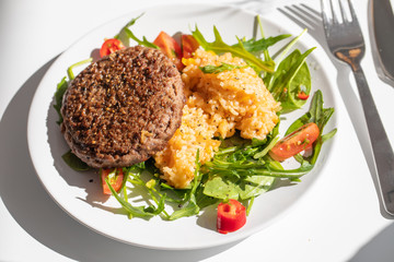 Close up of tasty patty with rice and salad on a white plate
