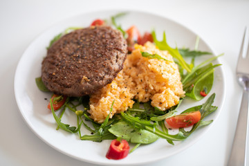 Close up of tasty patty with rice and salad on a white plate