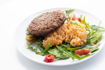 Close up of tasty patty with rice and salad on a white plate