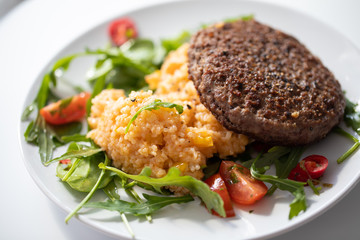 Close up of tasty patty with rice and salad on a white plate