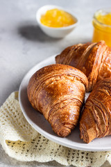 Fresh croissants. Freshly baked french croissants with jam on light grey background. 