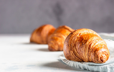 Fresh croissants on a grey linen napkin. Light grey concrete background. 