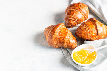 Fresh croissants on a grey linen napkin with jam. Light grey concrete background. 