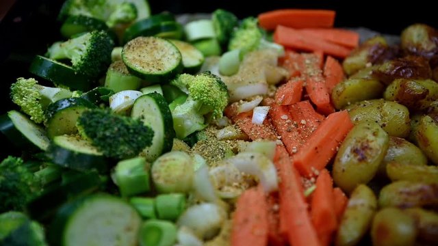 cooking tray full of green vegetables carrots, patatos, sprinkled with garlic