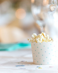 Popcorn box in pastel colors on a table in bright and soft light. Invite card with copy space and...