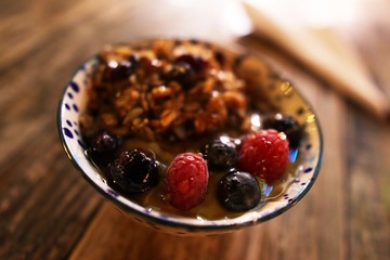 Raspberry, blueberry, and granola cereal bowl on rustic wood tabletop