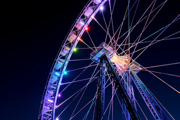 Amusement park at night - big ferris wheel with festive colorful illumination against blue evening...