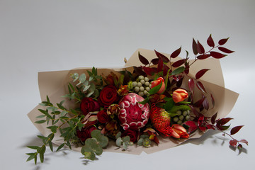 Magnificent bouquet of tulip, leucospermum, leucadendron, protea, rose on a gray background, selective focus