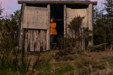 Fototapeta na wymiar Woman in Yellow Jumper in a Wooden hut looking out